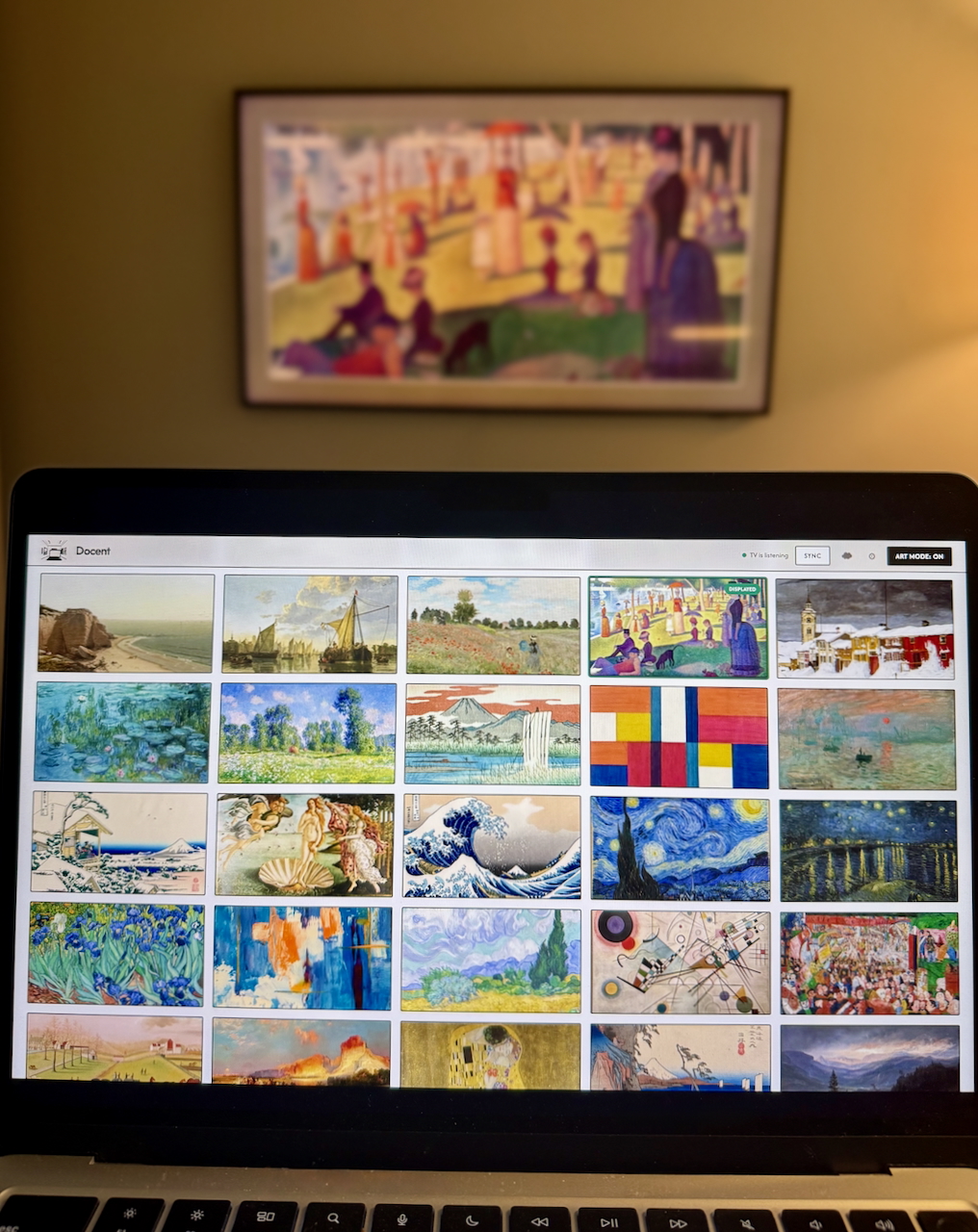 A laptop running Docent in front of a Samsung Frame TV displaying the selected artwork